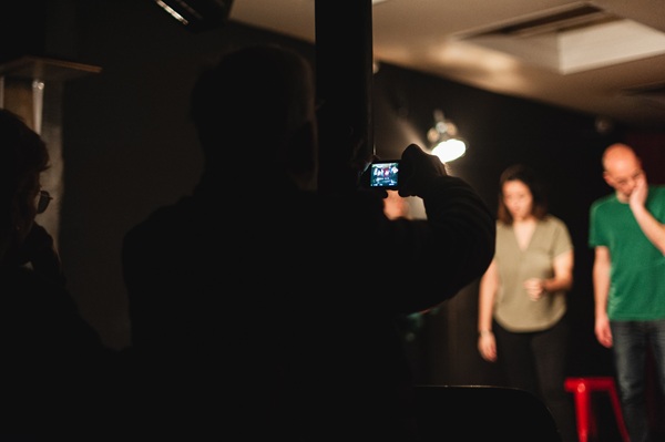 personne du public qui prend en photo les acteurs sur scène